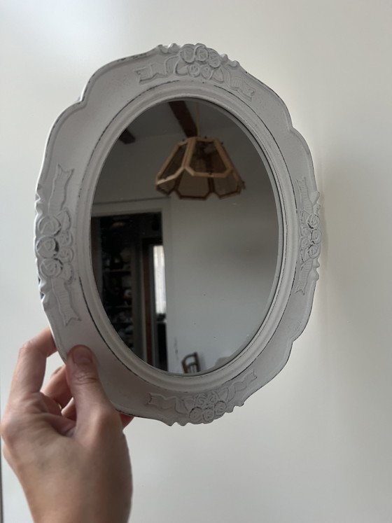 Image 1 of Specchio ovale in legno bianco con intagli floreali.