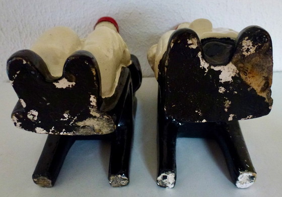 Image 1 of A set of decorative bookends depicting an elderly couple sitting on chairs.