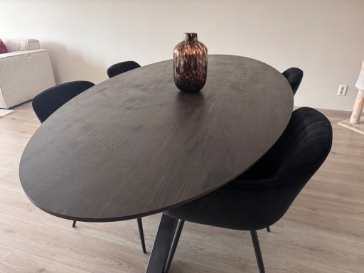 Oval dining table with dark brown top and black base