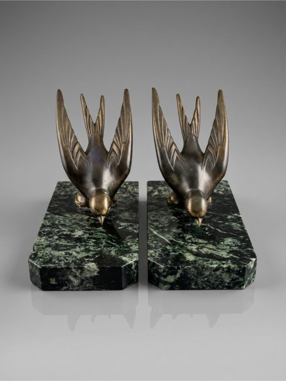 Image 1 of Een paar art-deco boekensteunen – zwaluwen van gepatineerd zink op groene marmeren voetstukken.