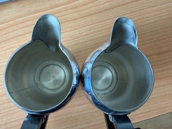Image 1 of 2 vintage Carlo Alessi stainless steel milk jugs with rounded tops and Bakelite handles.