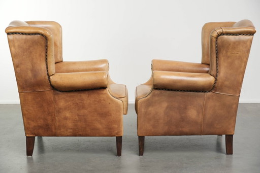 Dos hermosos sillones orejeros de piel de vaca clara con un estilo inglés atemporal y gran comodidad.
