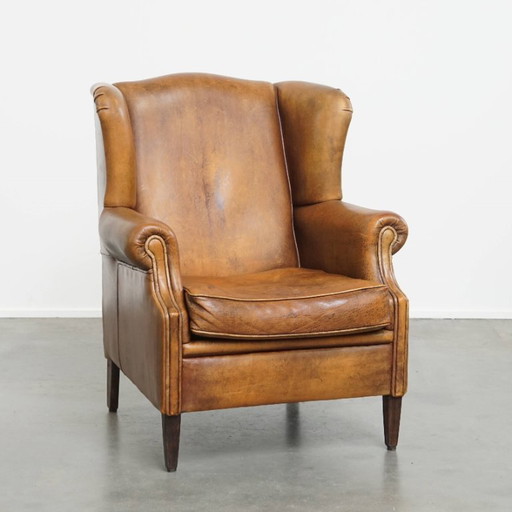 Karaktervolle vintage schapenleren oorfauteuil met een mooi patina