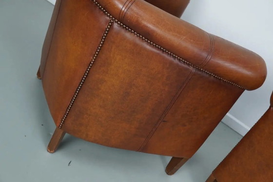 Image 1 of Dit paar cognackleurige leren clubfauteuils komt uit Nederland. Ze zijn bekleed met cognackleurig leer en zijn voorzien van meta