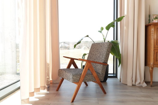 Poltrona lounge dal design vintage in tessuto mélange nero e legno color noce.