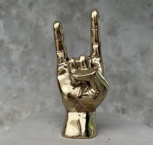 Sculpture en laiton poli faisant le signe de la main « Rock on ».