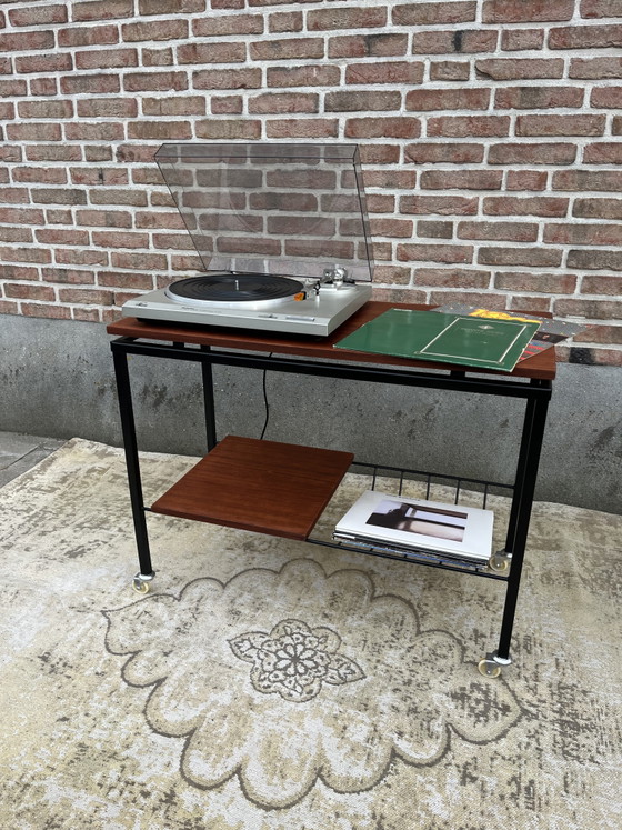 Image 1 of Mueble estéreo antiguo de teca con estructura de metal negro y ruedas giratorias.