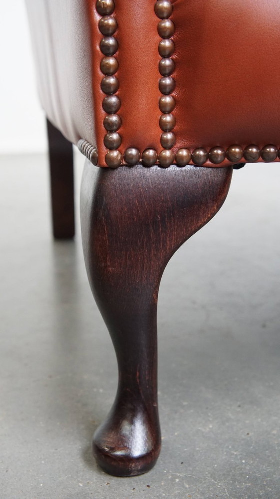 Image 1 of Elegante en comfortabele gladde Engelse rundleren chesterfield oorfauteuil met sierlijke pootjes