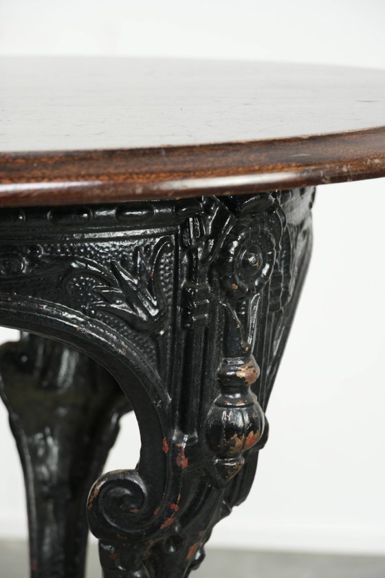 Image 1 of Antieke Engelse pub/ bistro/ bijzettafel uit de 19e eeuw met een gietijzeren onderstel en een rond houten tafelblad