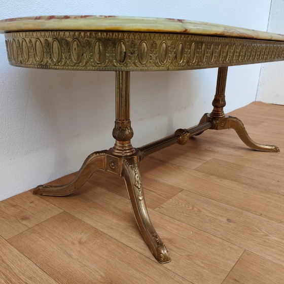 Image 1 of Table basse ovale de style Hollywood Regency avec plateau en marbre et piètement en laiton.