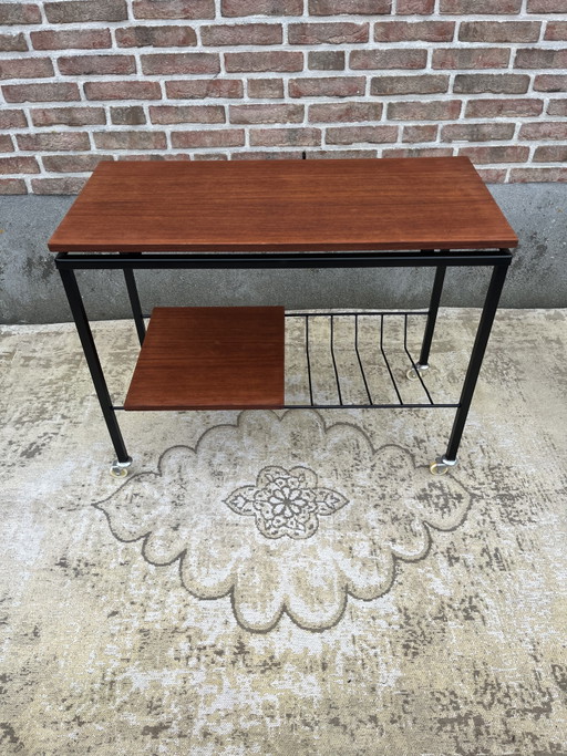 Mueble estéreo antiguo de teca con estructura de metal negro y ruedas giratorias.