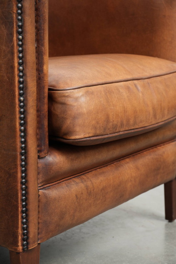 Image 1 of Poltrona club in montone color cognac caldo, rifinita con borchie decorative.