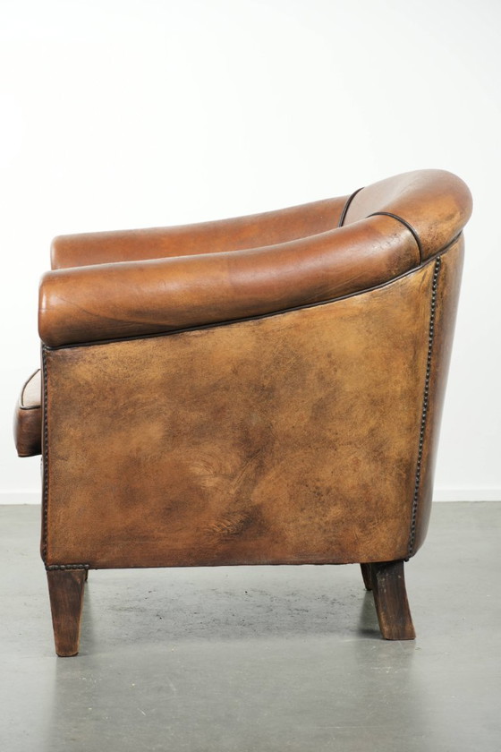 Image 1 of Schapenleren clubfauteuil met een mooie patina en een verfijnde afwerking met zwarte biezen