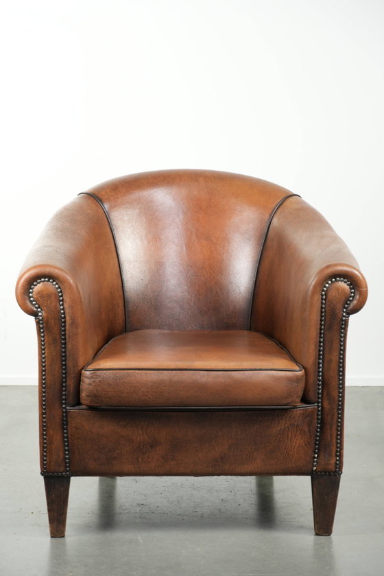 Image 1 of Schapenleren clubfauteuil met een mooie patina en een verfijnde afwerking met zwarte biezen