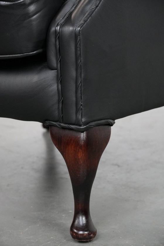 Image 1 of Smooth black cowhide Chesterfield wingback armchair in English style with color-matched piping