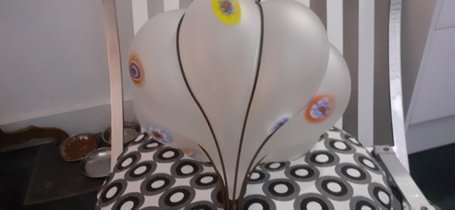 Lámpara colgante de vidrio lechoso con acentos de color.