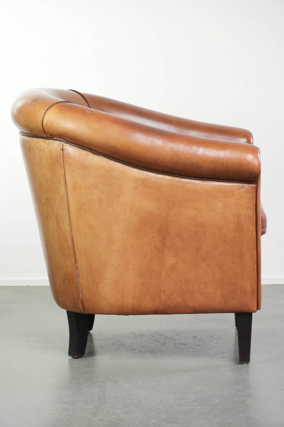 Image 1 of Vintage schapenleren clubfauteuil met een warme kleurstelling en afgewerkt met zwarte biezen