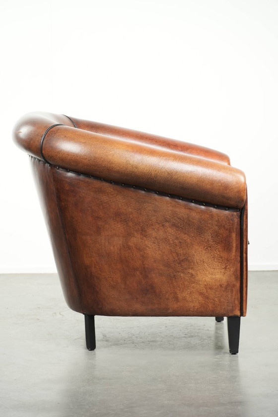 Image 1 of Mooie en karaktervolle schapenleren clubfauteuil met mooie diepe warme kleuren, zwarte biezen en een comfortabele zit