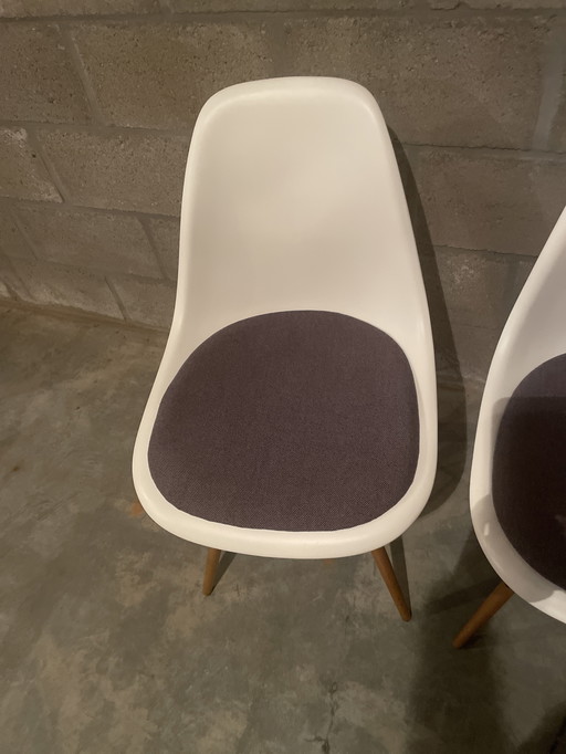 1 of 2 witte plastic stoelen van Charles Eames met antracietkleurig kussen