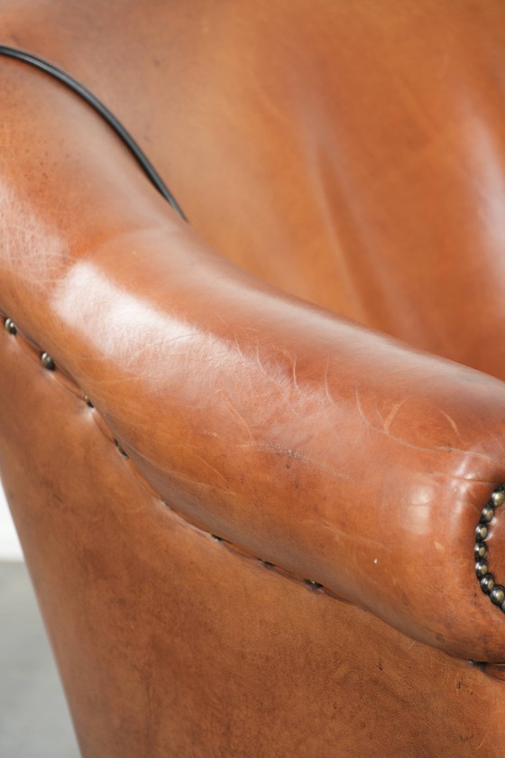 Image 1 of Amplio sillón club de estilo inglés, tapizado en piel de oveja, con acabado de clavos decorativos y ribetes negros.