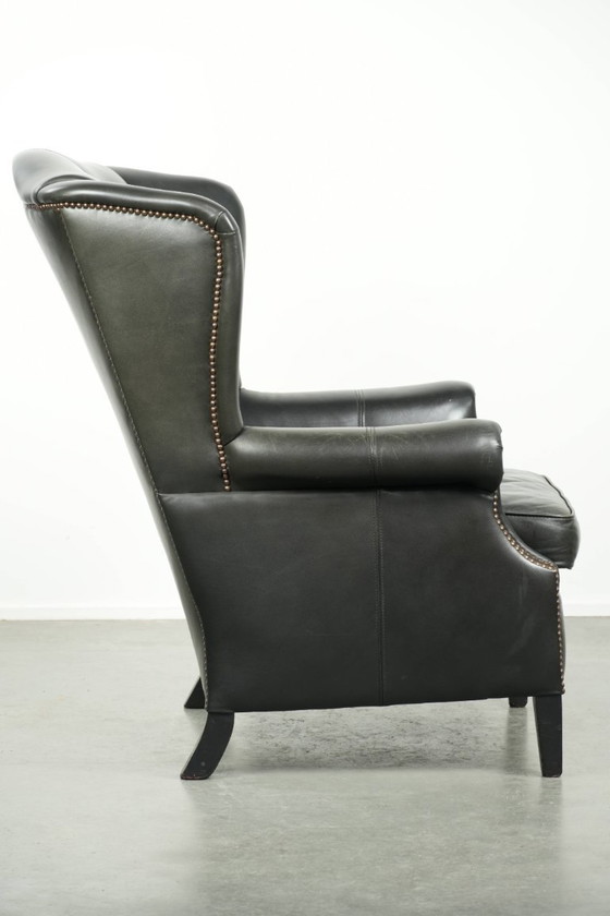 Image 1 of Zwarte rundleren oorfauteuil in een klassiek Engelse stijl