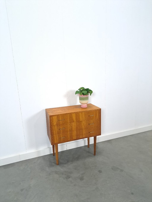 Cómoda danesa con patas altas y tiradores dorados.