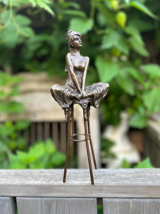 Bronzeskulptur einer sitzenden Dame auf einem Hocker