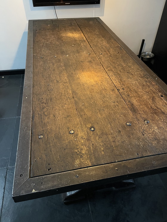 Image 1 of Industriele eettafel van oude werkbank met gietijzer onderstel y gelaste randen