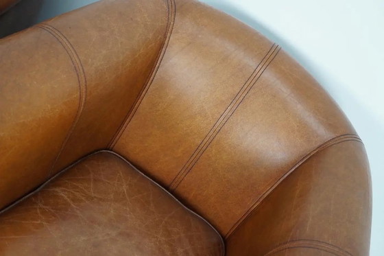 Image 1 of Dit paar cognackleurige leren clubfauteuils komt uit Nederland. Ze zijn bekleed met cognackleurig leer en zijn voorzien van meta