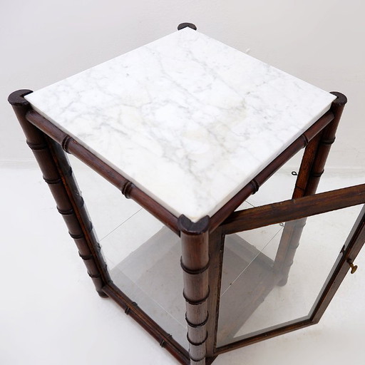 Vitrina de estilo de mediados de siglo con cristal y mármol efecto bambú.