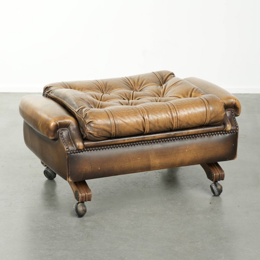Unique and elegant English Chesterfield ottoman in cowhide leather on wheels and finished with decorative nails.