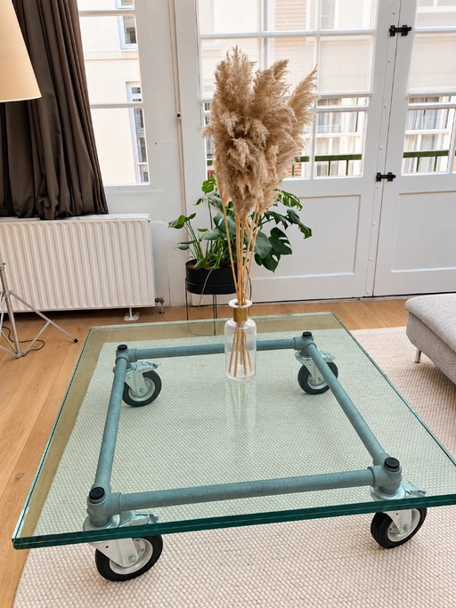 Mesa de centro industrial con tapa de cristal y ruedas