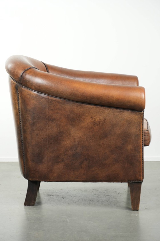 Image 1 of Schapenleren clubfauteuil met een mooie patina en een verfijnde afwerking met zwarte biezen