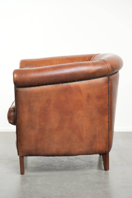 Image 1 of Poltrona club in montone color cognac caldo, rifinita con borchie decorative.