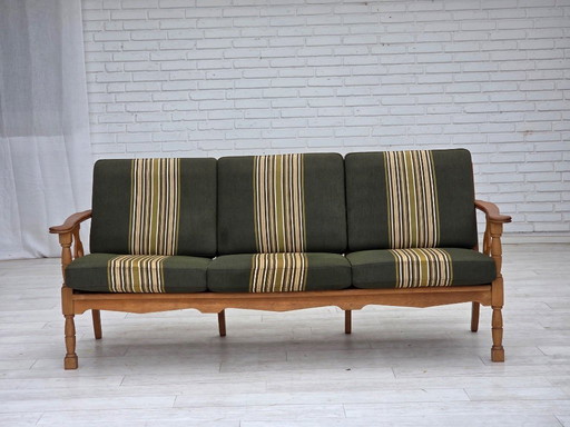 Deense driezitsbank uit de jaren 70, bekleed met groene meubelwol en gemaakt van massief eikenhout.