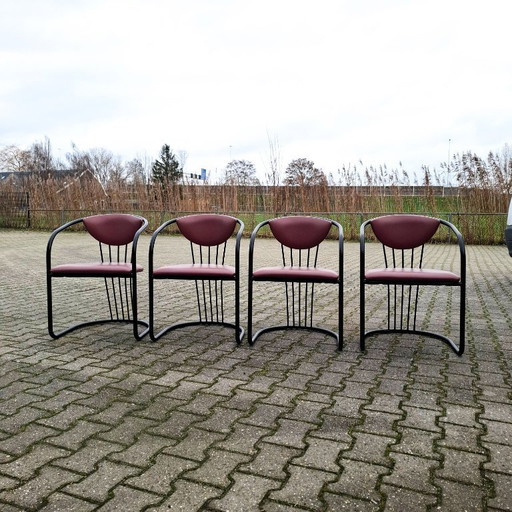 This is a set of four vintage 'Memphis' style chairs with a black metal frame and burgundy upholstery.