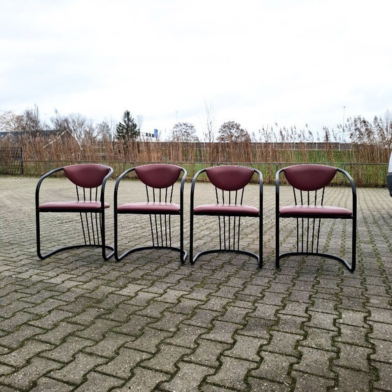 Image 1 of This is a set of four vintage 'Memphis' style chairs with a black metal frame and burgundy upholstery.