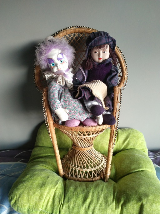 Two genuine porcelain dolls on an original wicker chair
