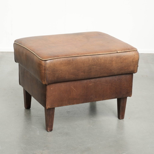 Characterful sheepskin leather footstool with a light brown color scheme and a vintage look