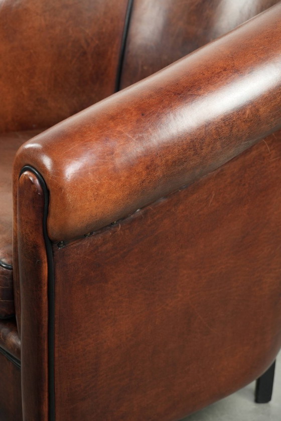 Image 1 of Mooie en karaktervolle schapenleren clubfauteuil met mooie diepe warme kleuren, zwarte biezen en een comfortabele zit