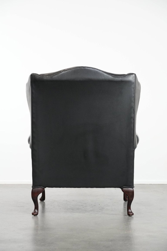 Image 1 of Smooth black cowhide Chesterfield wingback armchair in English style with color-matched piping