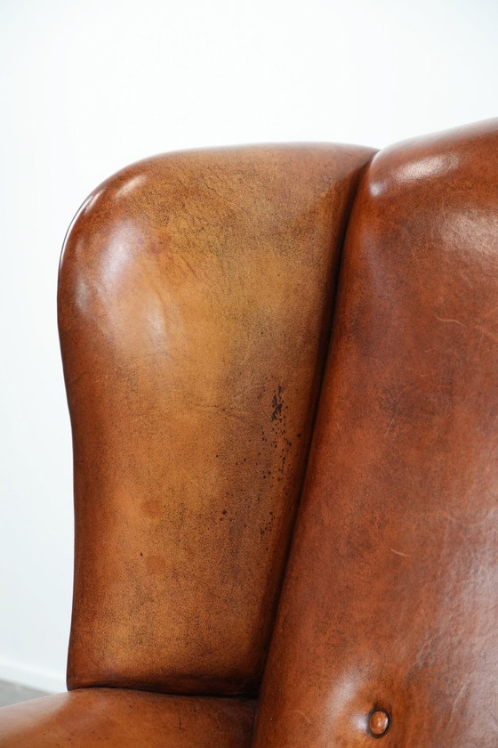 Image 1 of Grote schapenleren oorfauteuil met zwarte biezen en siernagels