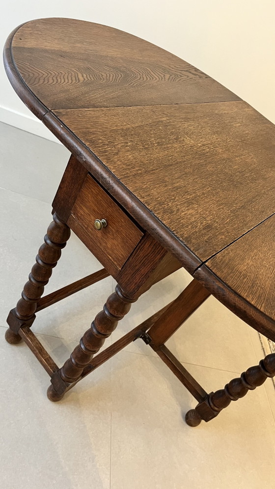 Image 1 of Mesa plegable de roble macizo estilo neojacobino inglés con patas abatibles.
Circa 1925–1940