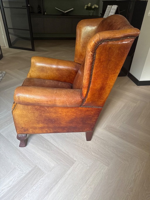 Poltrona antica con alette laterali in pelle di pecora, color cognac