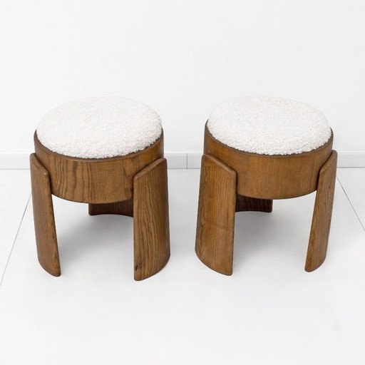 Een paar Art Deco-stijl krukjes van essenhout, bekleed met witte boucléstof.
