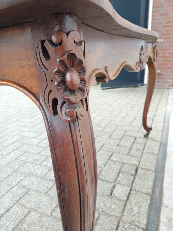 Image 1 of The antique dining table is made of mahogany and has a Louis XV style.
