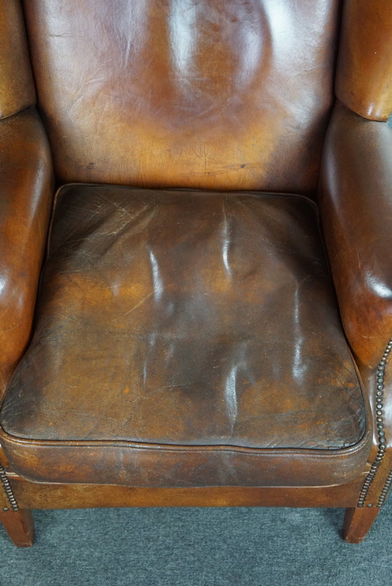 Image 1 of Oorfauteuil van cognac kleurig schapenleer afgewerkt met siernagels