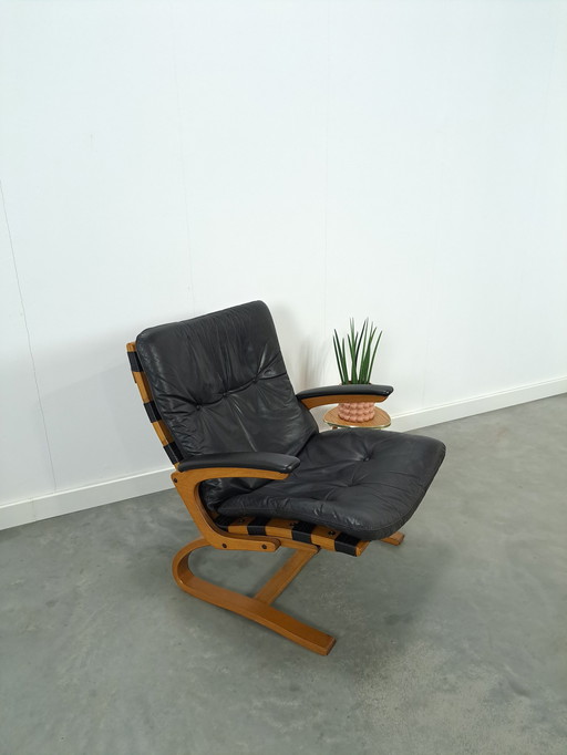 Zwart leren fauteuil met armleuningen en houten onderstel