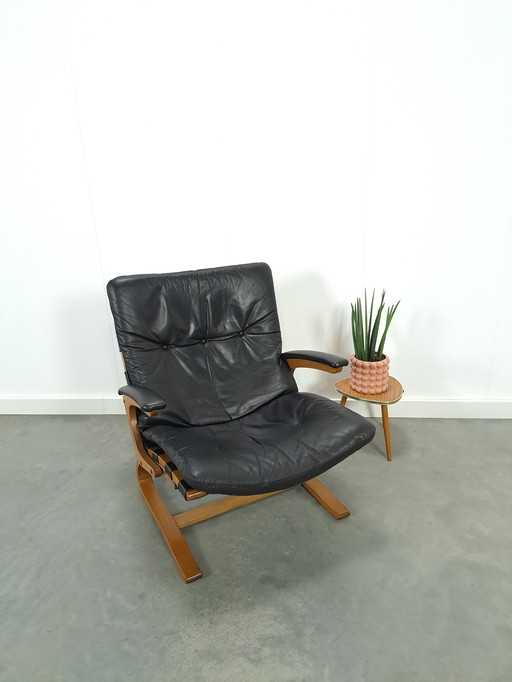 Zwart leren fauteuil met armleuningen en houten onderstel