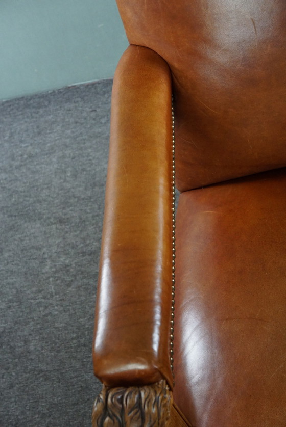 Image 1 of Fauteuil met leeuwenkoppen opnieuw bekleed met cognac kleurig rundleer